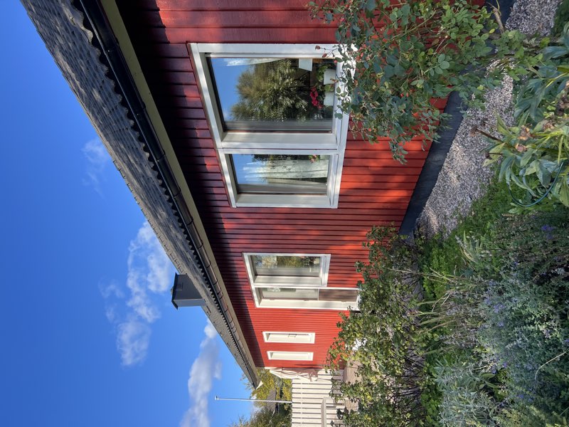 Rena fönster på rött hus med blå himmel